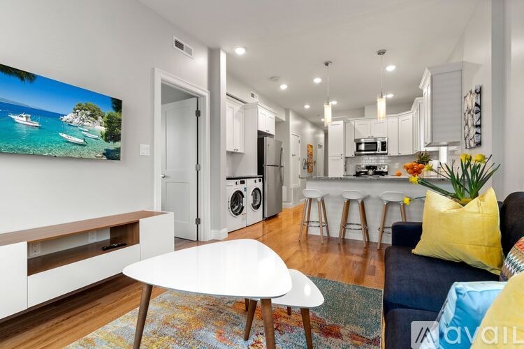 A modern living room with a white table and a painting of a beach scene on the wall.