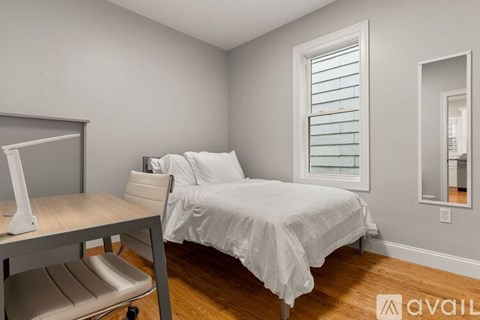 A bedroom with a bed, desk, and chair.