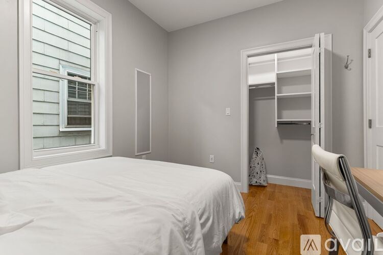 A bedroom with a bed, chair, and a closet with an open door.