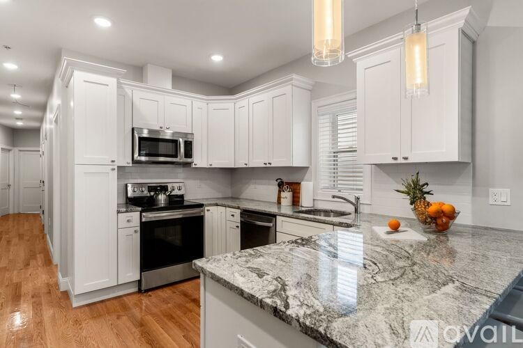 A kitchen with white cabinets and a marble countertop.