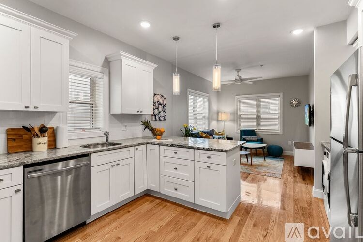 A kitchen with white cabinets and a wooden floor.