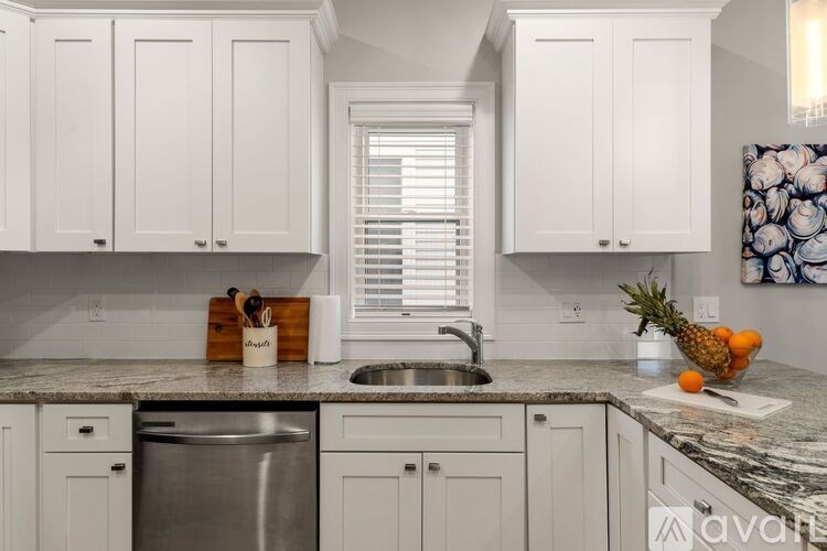 A kitchen with white cabinets and a granite countertop.