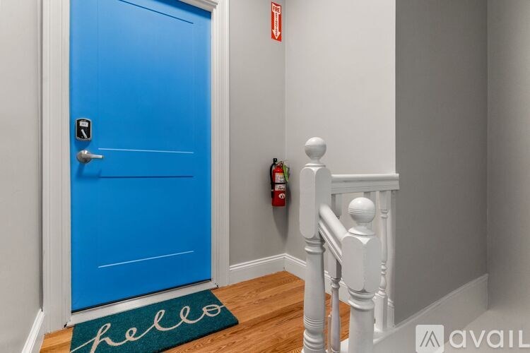 A blue door with a white mat that says hello on the floor.