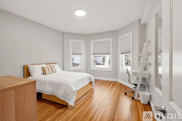 A bedroom with a bed, wooden floors, and a ladder.