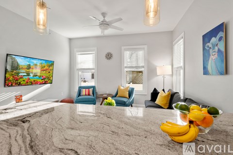 A living room with a grey carpet and a painting of a mouse on the wall.