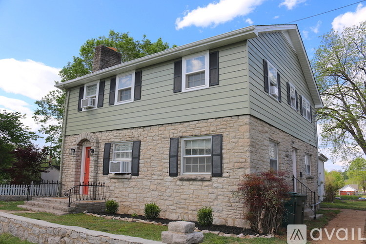 A two-story house with a red door and a stone facade.