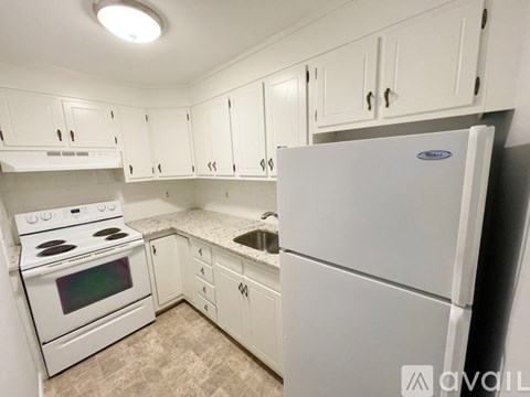 A white kitchen with a refrigerator, stove, and cabinets.