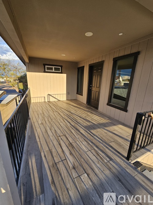 A wooden deck with a railing and a small window on the side of a building.