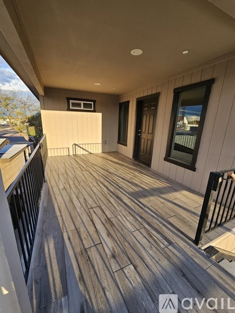 A wooden deck with a railing and a small window on the side of a building.
