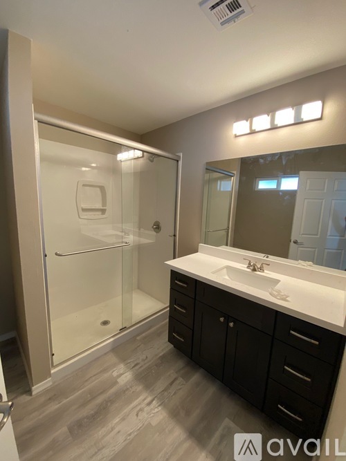 A bathroom with a sink, mirror, and shower.
