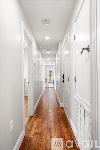 A long hallway with wood floors and white walls.