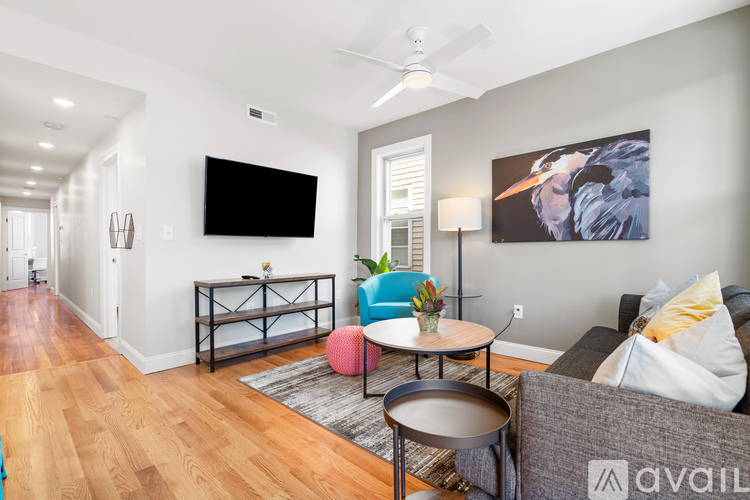 A living room with a couch, a chair, a table, a television, and a painting on the wall.