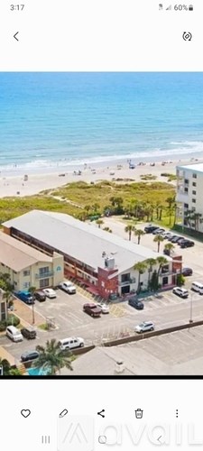 A beachfront view with a building and cars parked in front.