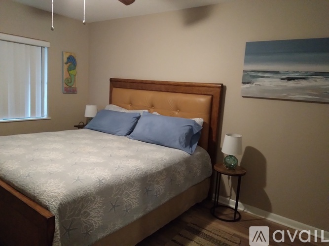 A bedroom with a bed, a nightstand with a lamp, and a painting on the wall.