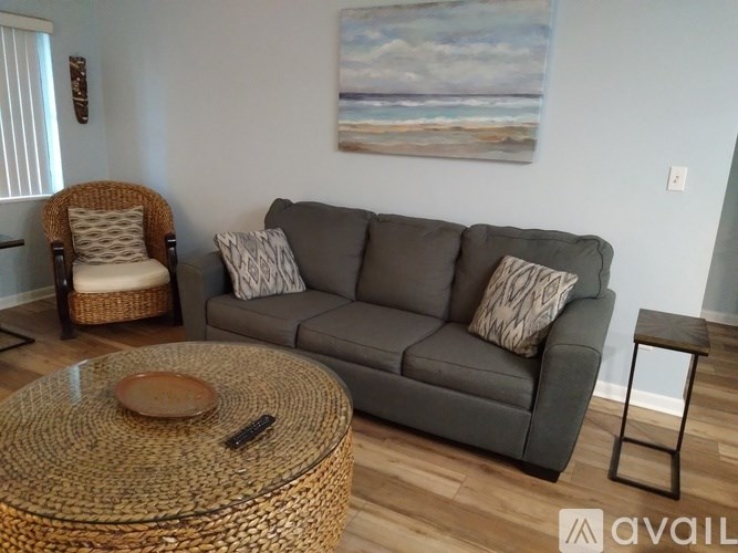 A living room with a grey couch, a wicker chair, and a coffee table.