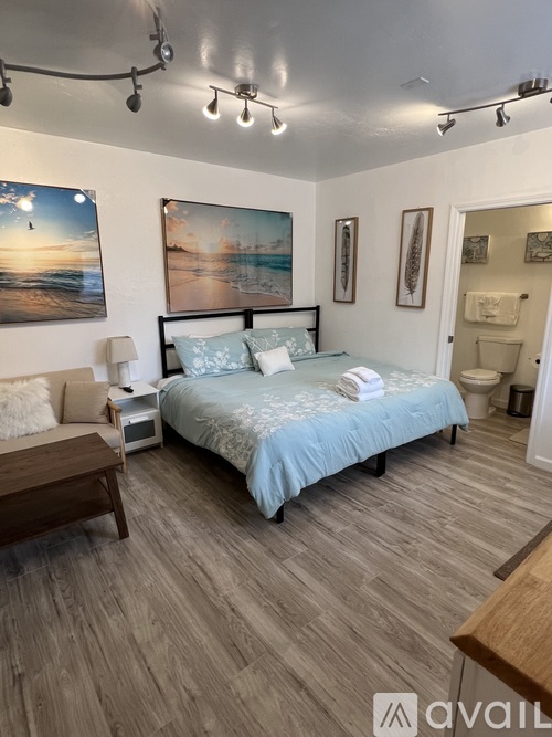 A bedroom with a bed, nightstand, and a painting on the wall.