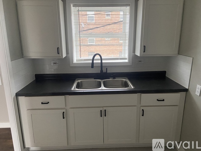A kitchen with a black countertop and white cabinets.