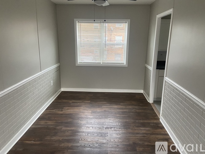 A room with wooden flooring and a window with blinds.