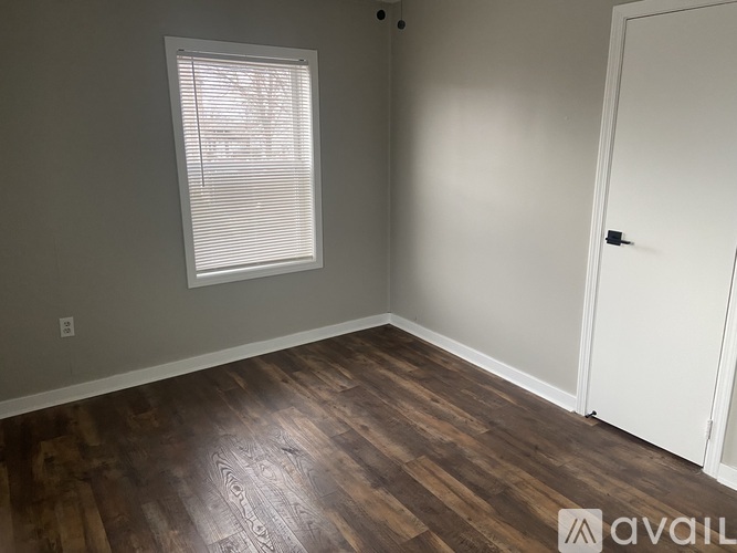 A room with wooden flooring and a window with blinds.