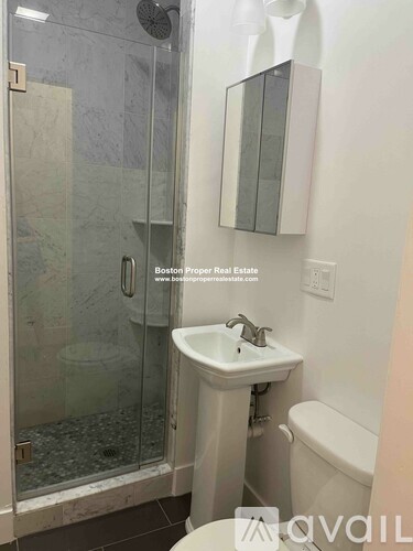 A bathroom with a glass shower door and a white toilet.