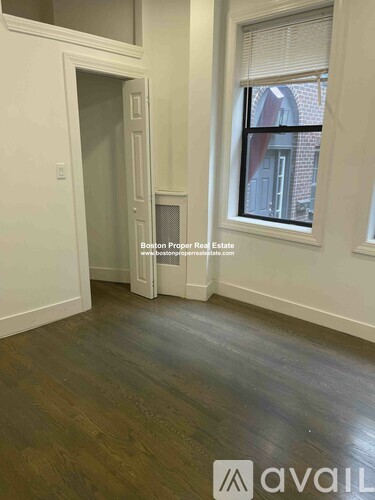 A room with wooden floors and a window showing a brick building outside.