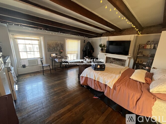 A bedroom with a bed, a television, and a window.