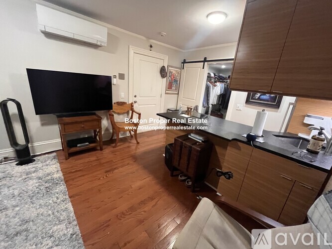 A living room with a flat screen TV and a wooden floor.