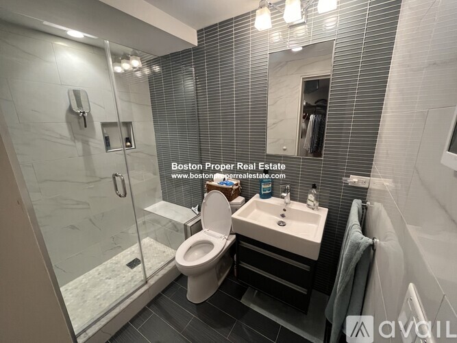 A modern bathroom with a glass shower stall and a toilet.