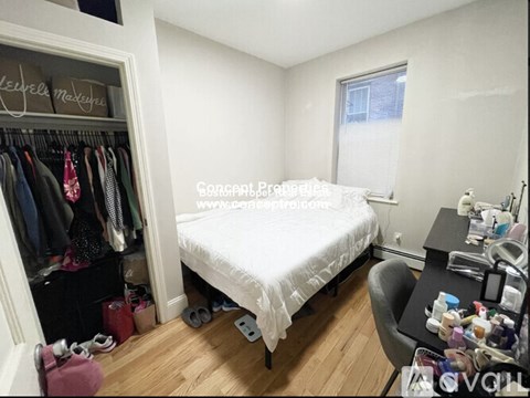 A bedroom with a bed, desk, and closet.