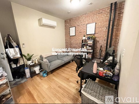 A room with a brick wall and a grey couch.