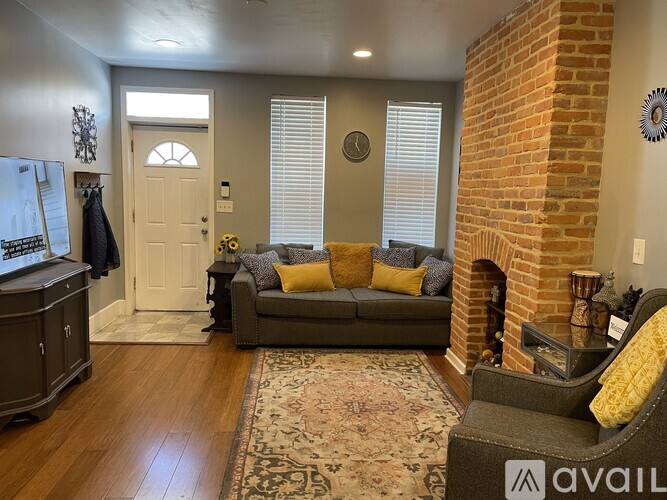 A living room with a grey couch and a fireplace.