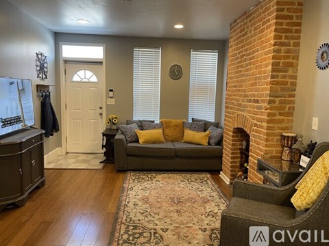 A living room with a grey couch and a fireplace.