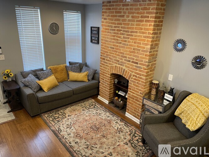 A living room with a grey couch, a fireplace, and a rug.