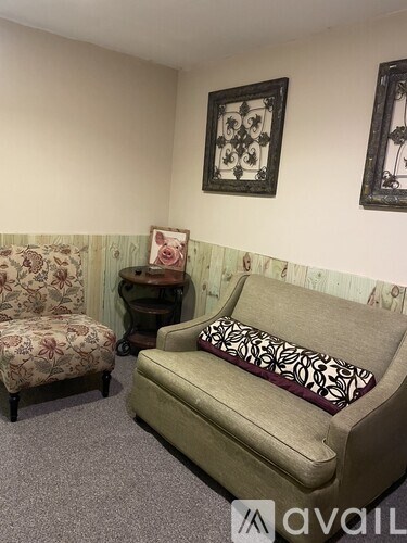 A living room with a couch, chair, and two picture frames on the wall.