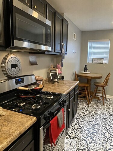 A kitchen with black cabinets and a stove top oven.