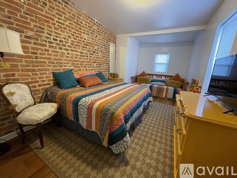 A bedroom with a brick wall and a bed with a colorful blanket.