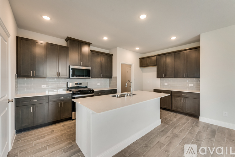 A modern kitchen with dark brown cabinets and a white island.