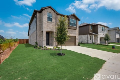 A house with a brown brick exterior and a green lawn in front.