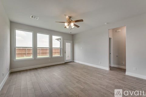 A spacious room with a ceiling fan and large windows.