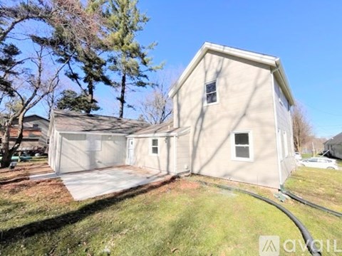 A two-story house with a garage is situated in a grassy area.