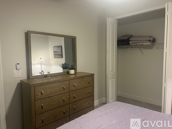 A bedroom with a wooden dresser and a mirror above it.