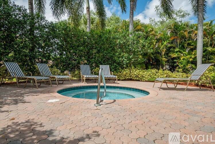 A pool surrounded by palm trees and lounge chairs.
