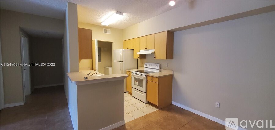 A kitchen with white appliances and wooden cabinets is available for rent.