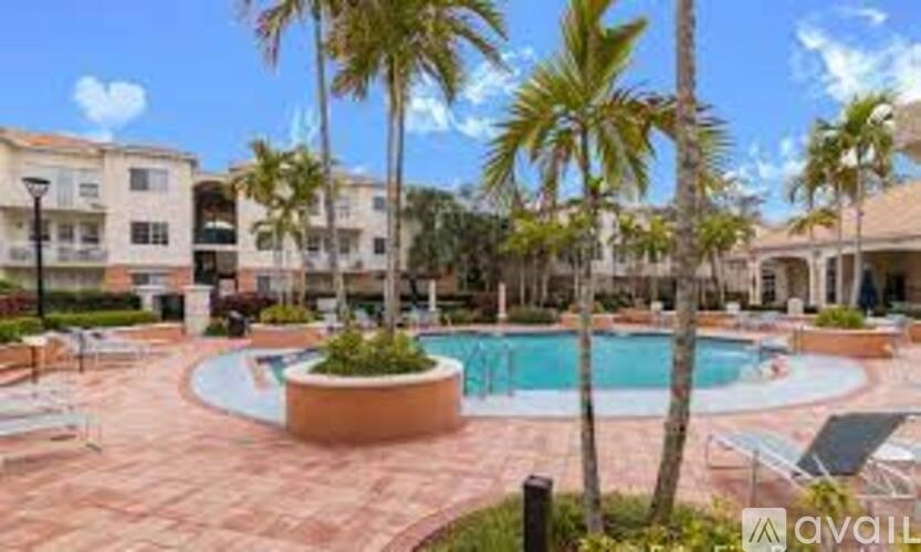 A pool surrounded by palm trees and lounge chairs.