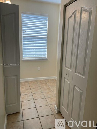 A room with a door and a window with blinds.