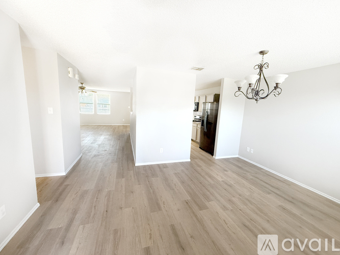 A long hallway with a rug on the floor and a kitchen area visible in the distance.
