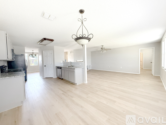 A spacious living room with a chandelier and a ceiling fan.