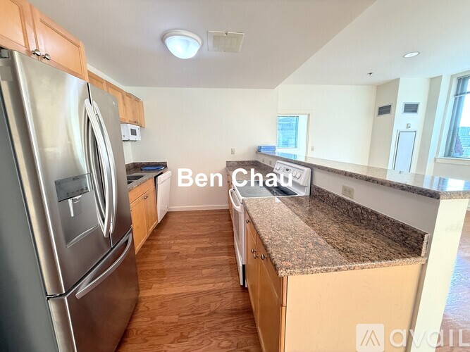 A kitchen with a refrigerator on the left and a counter with a sink and a cutting board on the right.