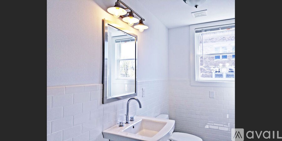 A white bathroom with a sink, mirror, and toilet.
