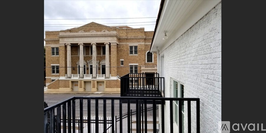 A white brick building with a black railing in front.